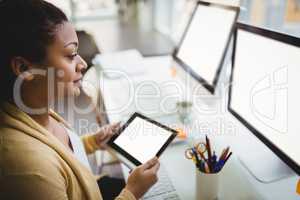 Businesswoman looking at computer while using digital tablet in