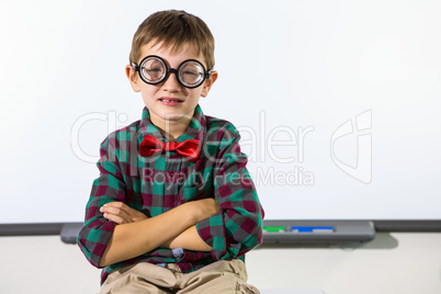 Boy sitting against whiteboard in classroom