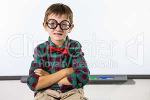 Boy sitting against whiteboard in classroom