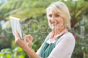Happy mature female gardener using digital tablet
