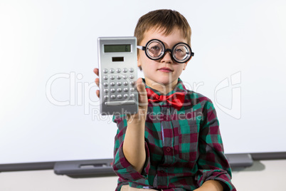 Portrait of elementary boy holding calculator in classroom