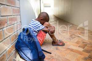 Boy sitting alone on school corridor