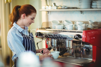 Young waitress using coffee maker at cafeteria