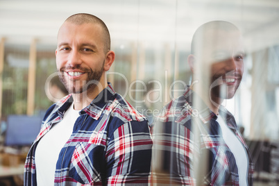 Businessman standing by glass window in creative office