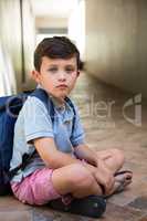Boy sitting on corridor in school