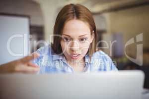 Surprised businesswoman working on laptop in office