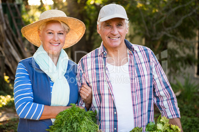 Portrait of happy couple with vegetables at garden