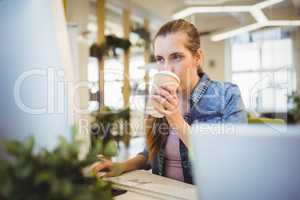 Businesswoman having coffee while working in office