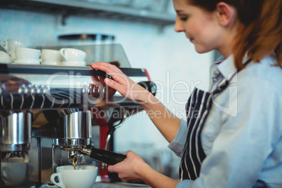 Barista using espresso machine to pour coffee in cup