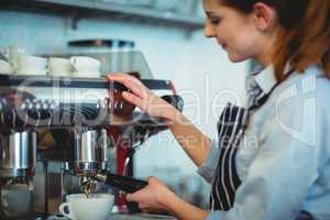 Barista using espresso machine to pour coffee in cup