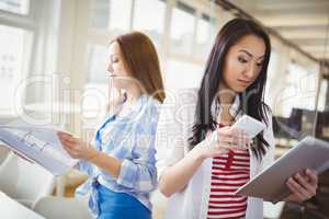 Female colleagues holding files and mobile phone in office