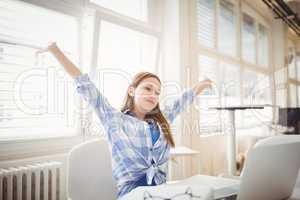 Succesfull businesswoman with arms outstretched while sitting at