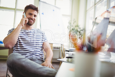 Portrait of businessman using mobile phone while sitting in offi