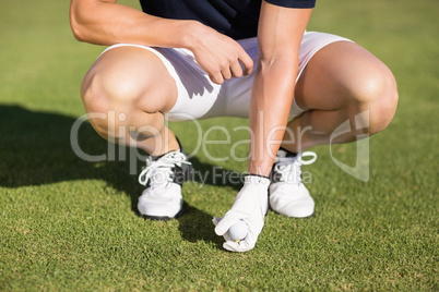 Low section of man placing golf ball on tee