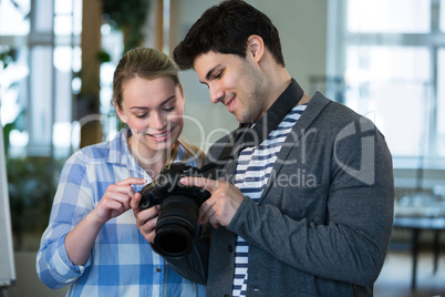Happy photographer showing picture to colleague at creative offi