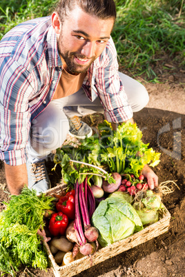 Portrait of happy gardener crouching with vegetables at garden