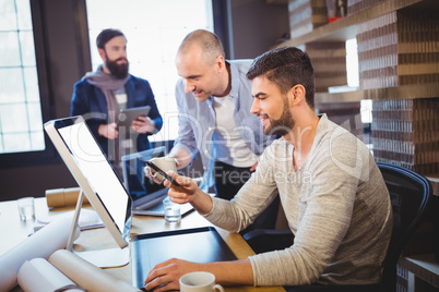 Male creative coworkers discussing over computer