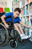 Portrait of handicapped boy searching books in library