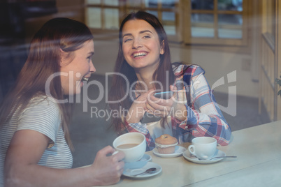 Cheerful women with cellphone at coffee shop
