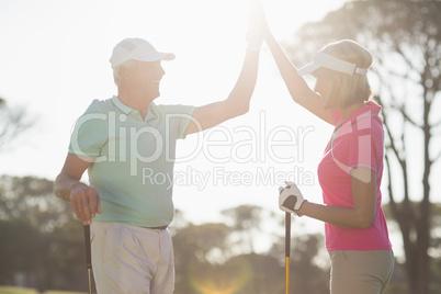 Happy golfer couple giving high five