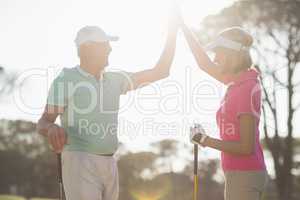 Happy golfer couple giving high five