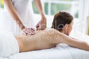 Midsection of masseuse giving massage to woman