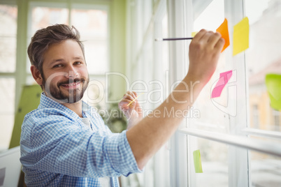 Portrait of businessman writing on adhesive notes at office