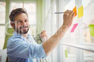 Portrait of businessman writing on adhesive notes at office