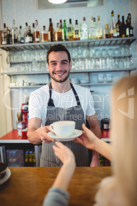 Portrait of confident barista serving coffee to customer at cafe