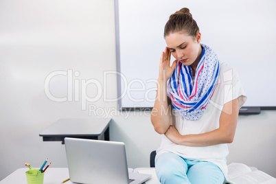 Teacher suffering from headache while sitting in classroom