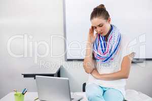Teacher suffering from headache while sitting in classroom