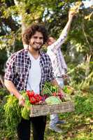 Portrait of happy hipster gardener with vegetables and colleague