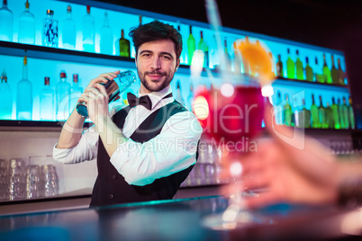Handsome barkeeper preparing cocktail at bar counter