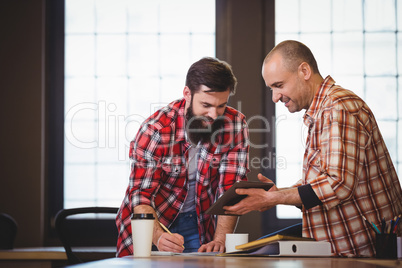 Male coworkers discussing over digital tablet