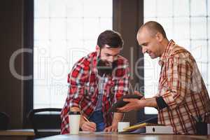 Male coworkers discussing over digital tablet