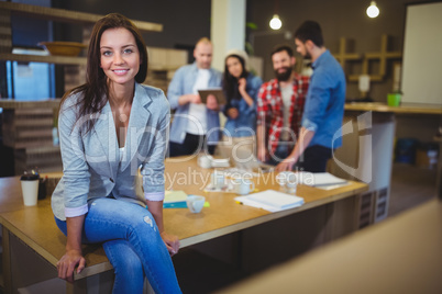 Smart businesswoman sitting on table in office