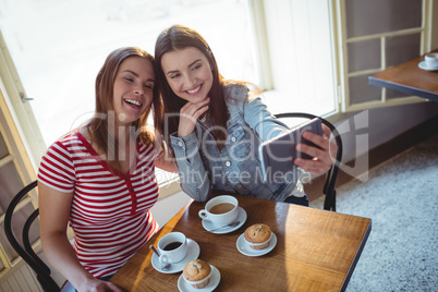 High angle view of happy friends taking selfie at cafe