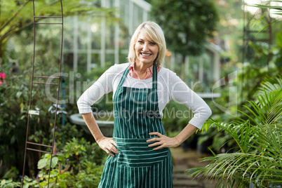 Mature woman standing with hand on hip at greenhouse