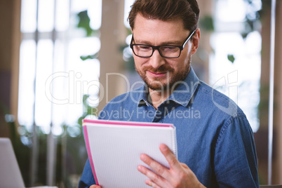 Confident executive reading documents at creative office