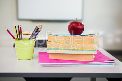 Apple with books and desk organizer on table in classroom