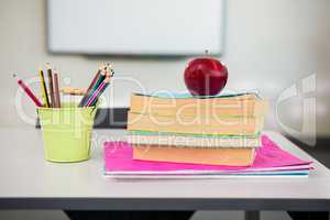 Apple with books and desk organizer on table in classroom