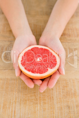 Person holding grapefruit slice at table