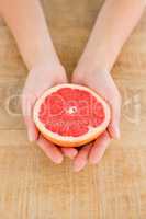 Person holding grapefruit slice at table