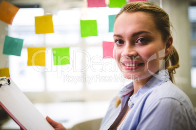 Businesswoman holding note pad against sticky notes