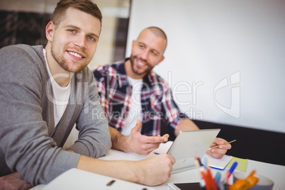 Young businessmen using digital tablet at desk in office