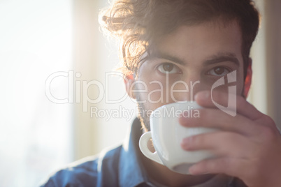 Close-up of young customer drinking coffee at cafe