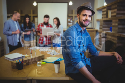 Stylish businessman sitting on table in creative office