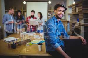 Stylish businessman sitting on table in creative office