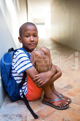Elementary boy sitting on corridor in school
