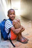 Elementary boy sitting on corridor in school